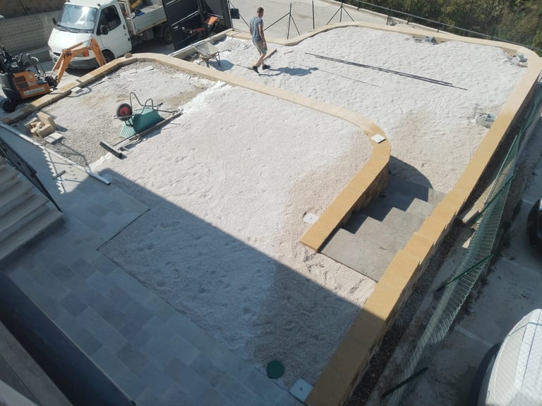 Aerial view of flat roof under construction with workers, lumber framing, and parked vehicles visible