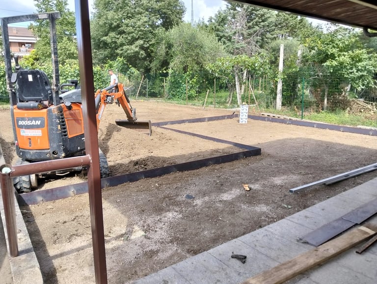 Orange Bobcat mini excavator on construction site with dirt area and trees in background